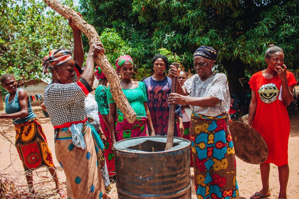Group of women in colorful traditional clothing cooking outdoors.